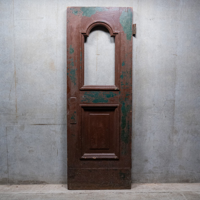 Antique c.1880 solid wood NYC brownstone door with arched opening and original distressed brown and green painted surface. | Scott Landon Antiques and Interiors.