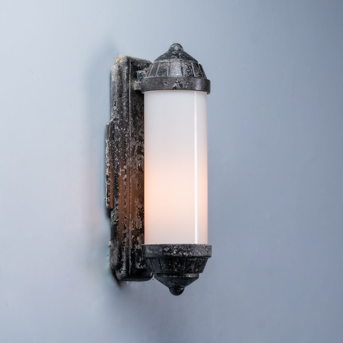     Cast aluminum wall sconce with elongated opal-glass shade and worn dark finish. | Scott Landon Antiques and Interiors.