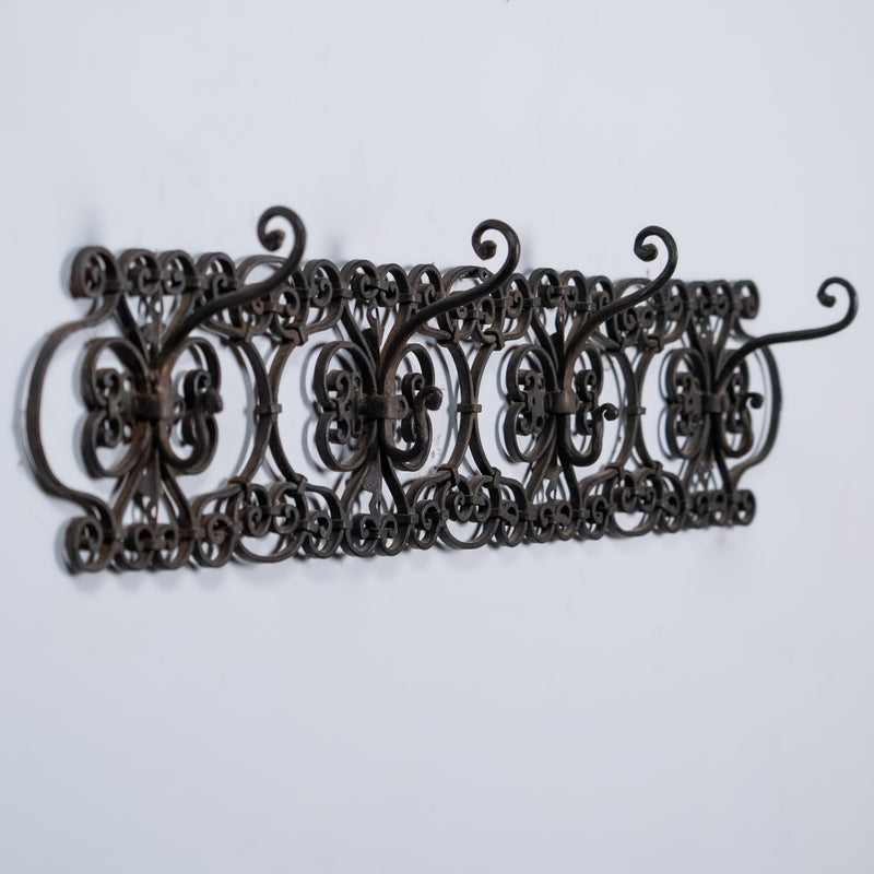 Antique French wrought iron wall rack with scrolling decorative details and aged black patina.