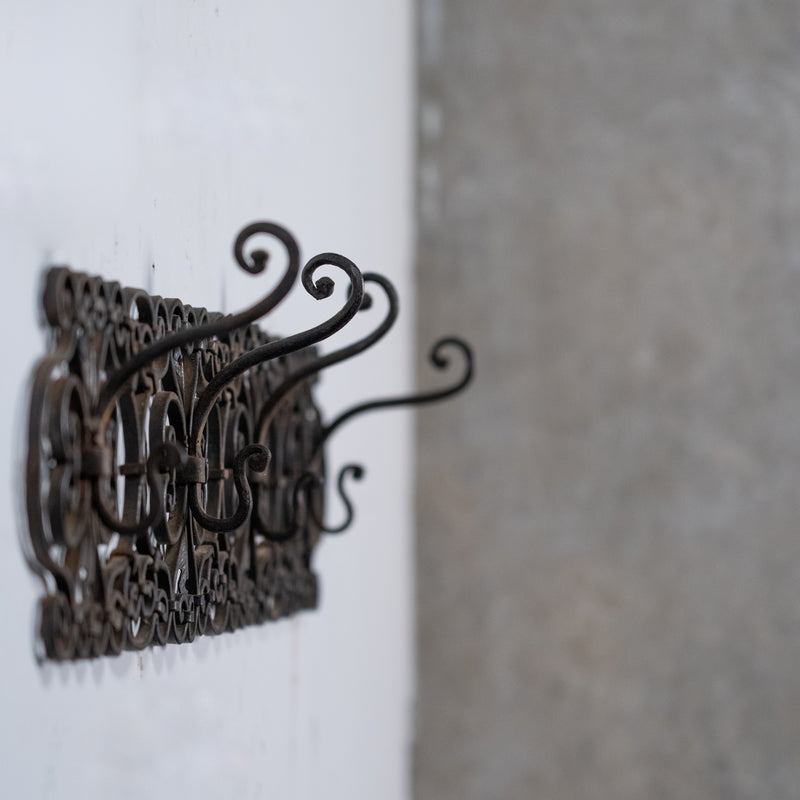 Antique French wrought iron wall rack with scrolling decorative details and aged black patina.