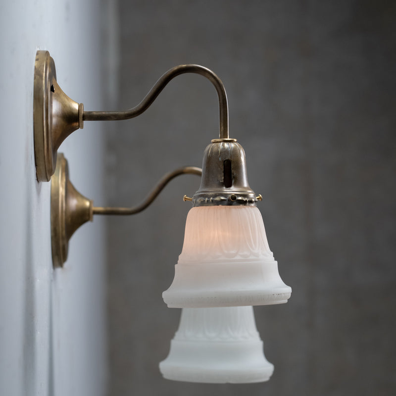 Pair of antique brass wall sconces with frosted satin glass shades and curved gooseneck arms
