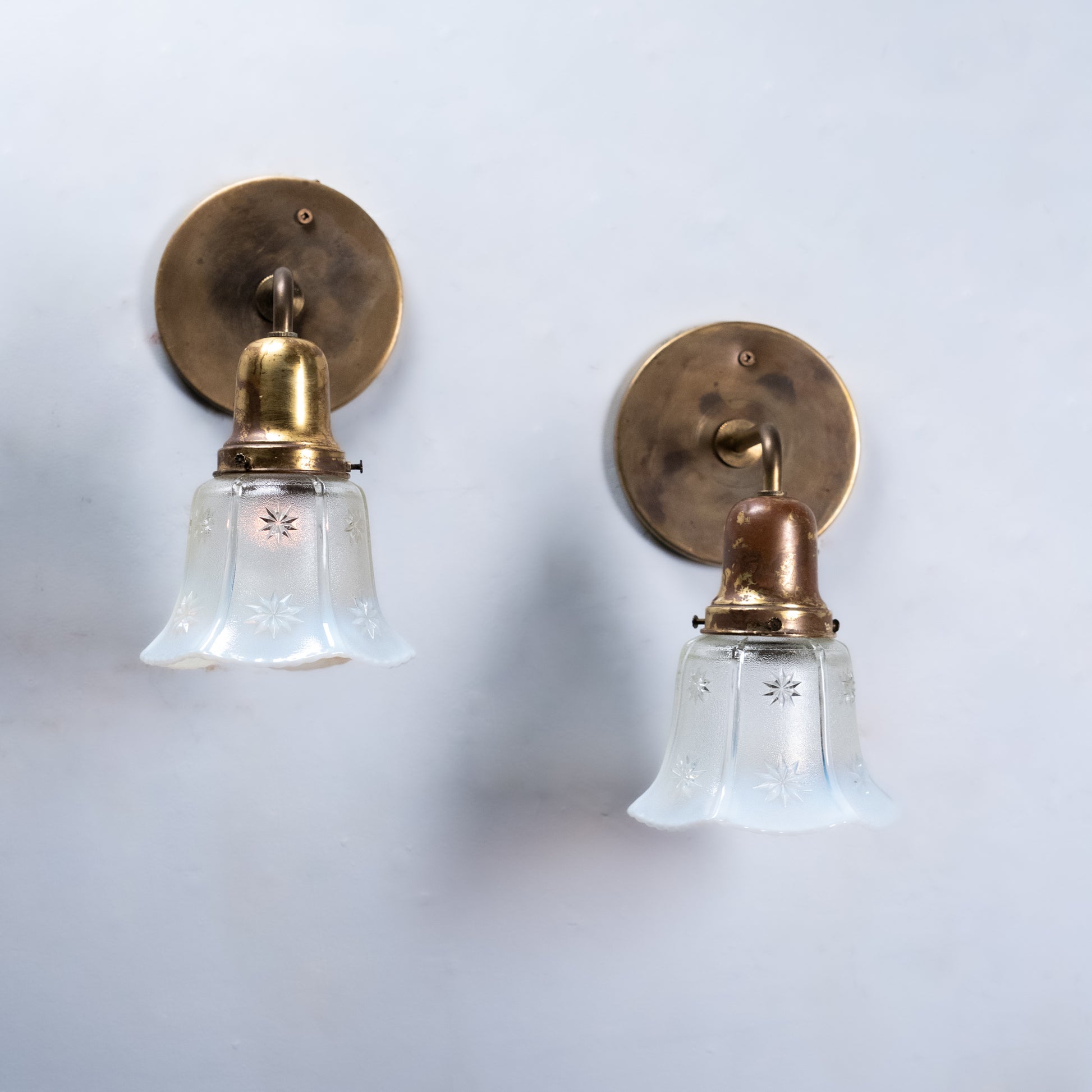 Pair of antique Edwardian brass wall sconces with original opalescent starburst glass shades and aged brass finish, circa 1915.