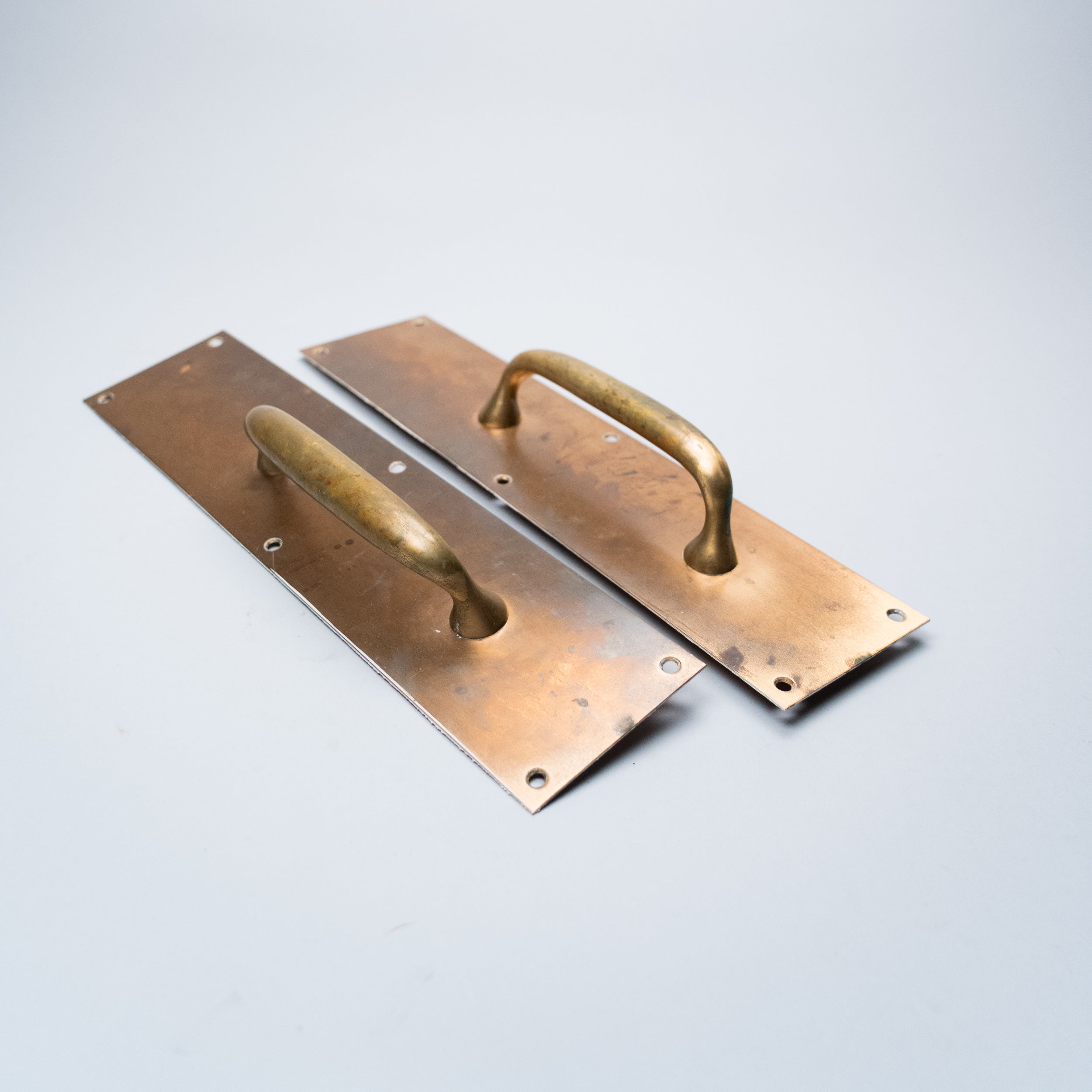 Pair of vintage Art Deco brass architectural door pull handles with rectangular backplates and original aged patina, circa 1930