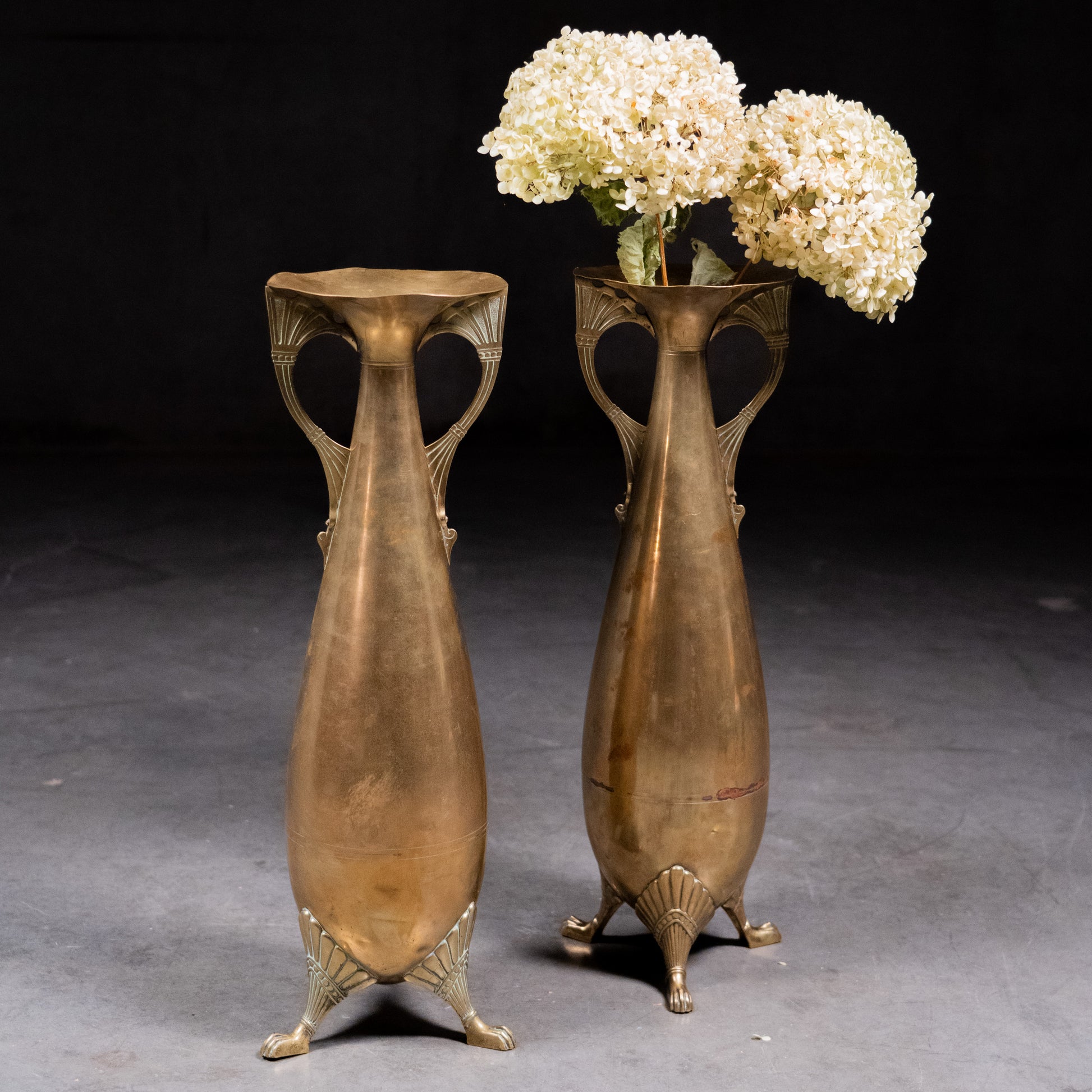 Pair of German Art Nouveau WMF brass vases with flowing openwork handles, paw feet, and original antique patina, circa 1900–1910.