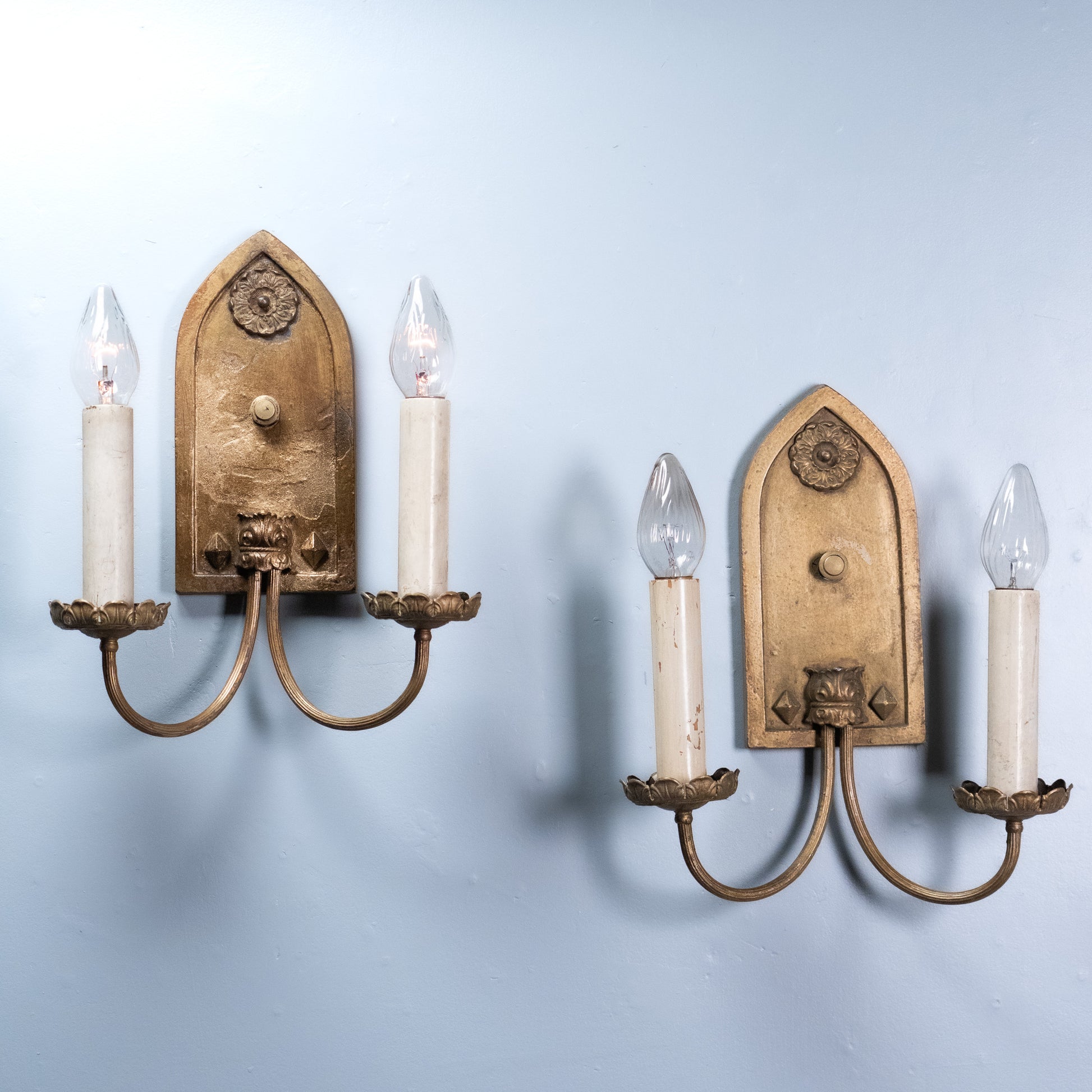 Antique Gothic Revival double arm wall sconce with gilt finish and pointed arch backplate, circa 1930.