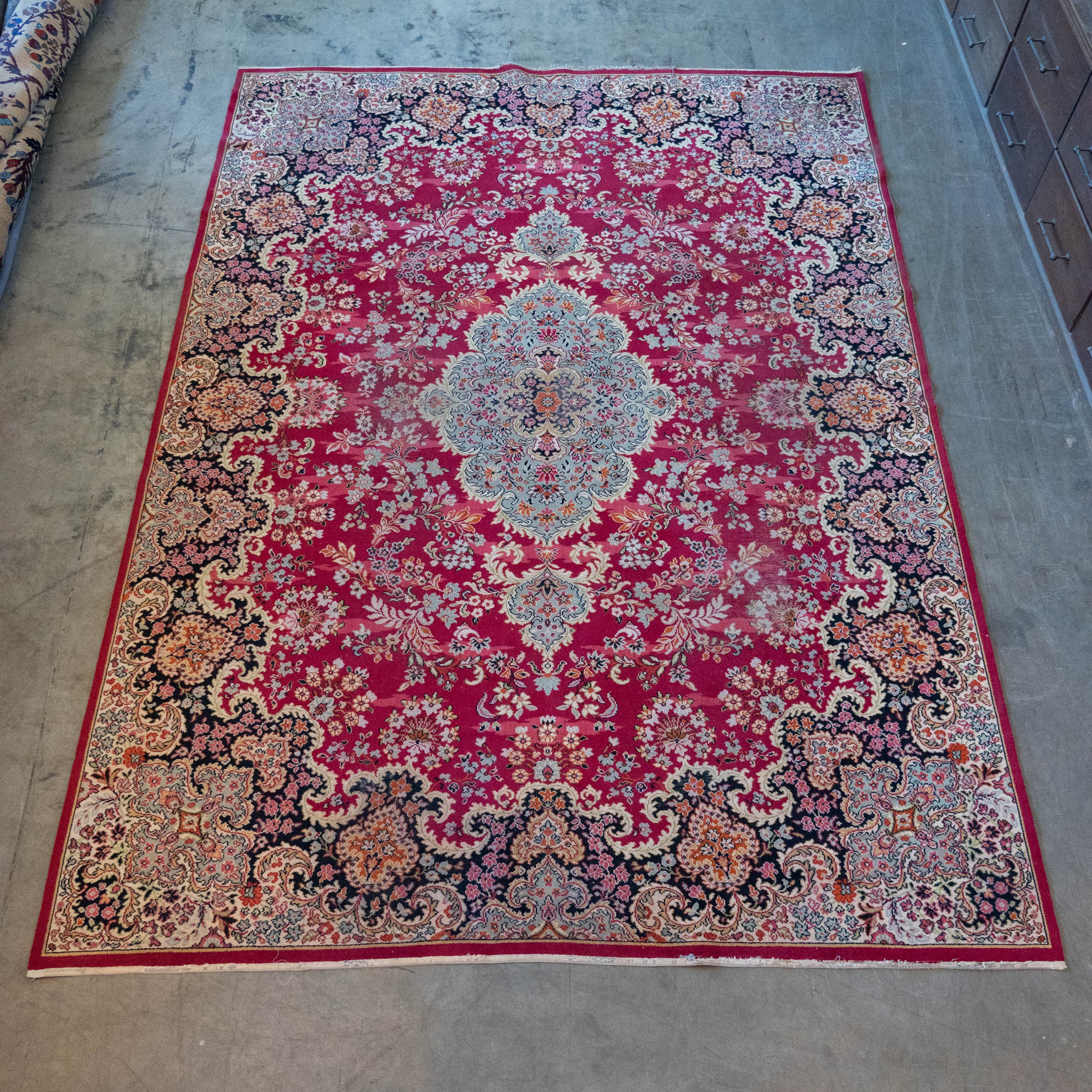 Vintage Persian style machine-made Kerman area rug with raspberry red floral pattern and ivory border measuring approximately 9 by 13 feet. | Scott Landon Antiques and Interiors.