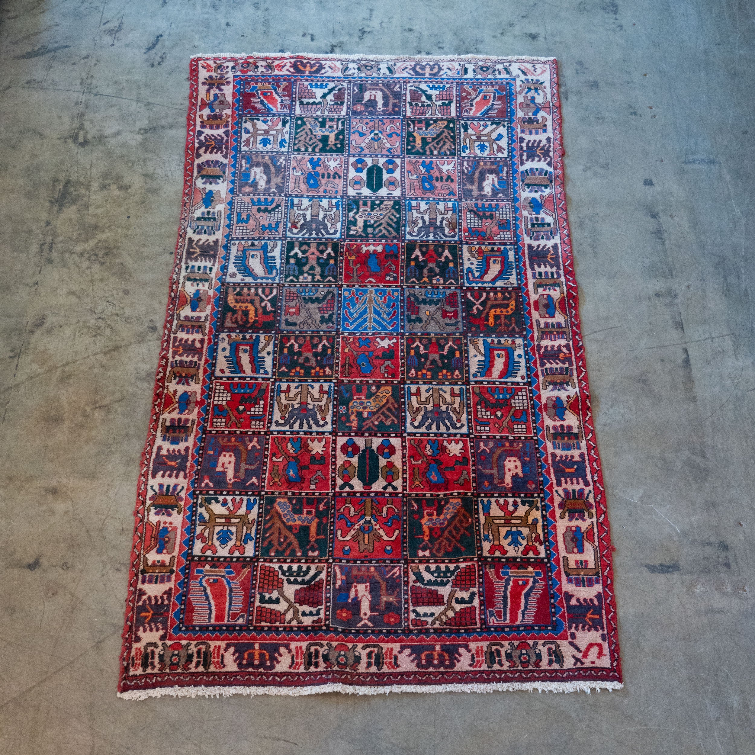 Antique Persian Bakhtiari garden rug with Khesti panel design featuring birds, animals and geometric motifs in red, blue and ivory.