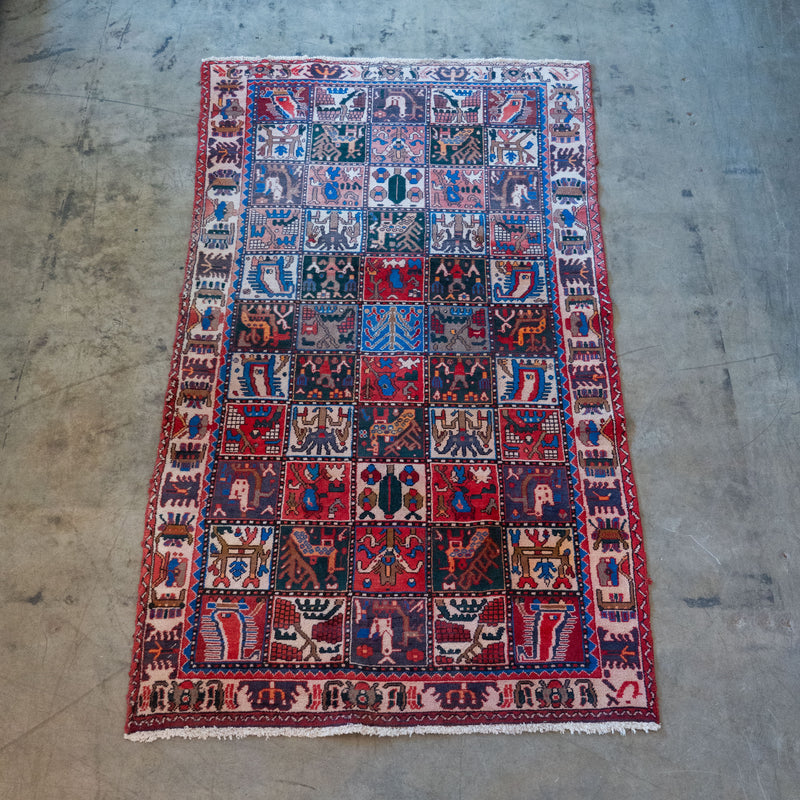 Antique Persian Bakhtiari garden rug with Khesti panel design featuring birds, animals and geometric motifs in red, blue and ivory.