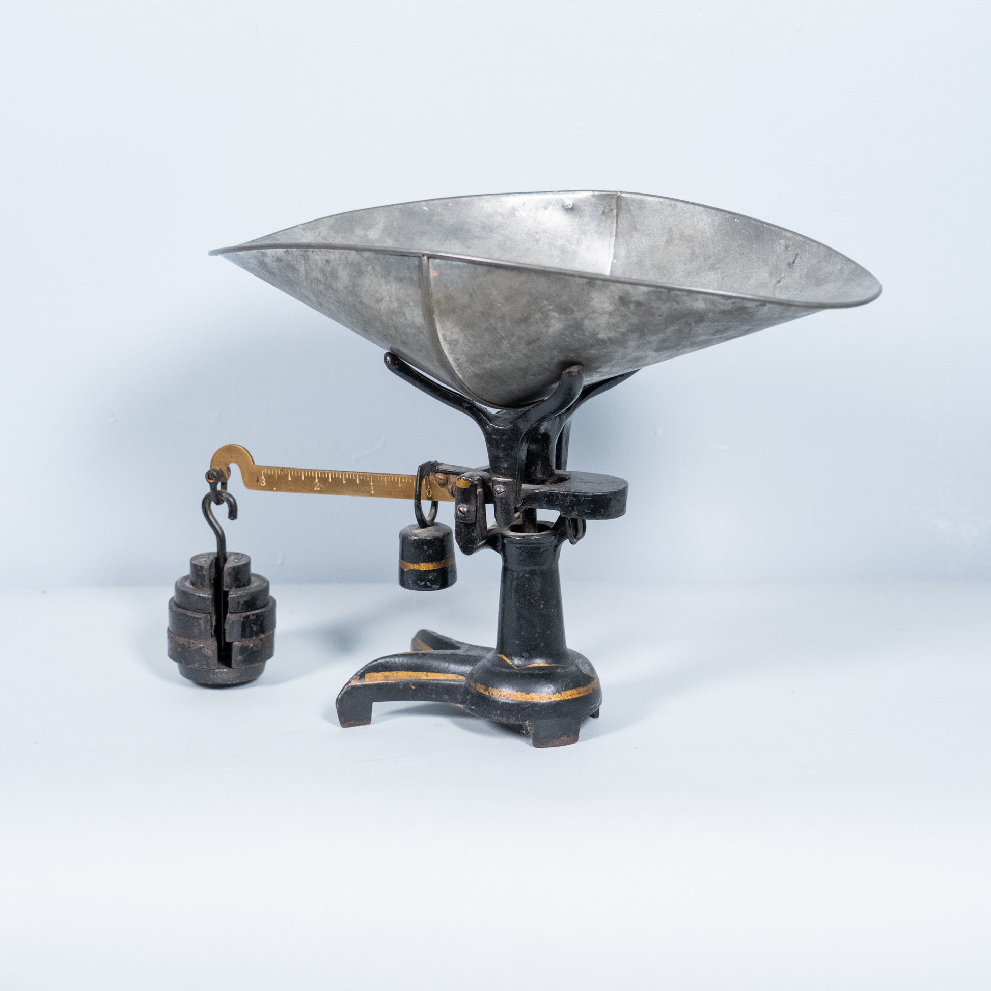 Antique cast iron counter balance scale with original galvanized scoop, brass graduated beam, and cast iron counterweights, vintage early 20th-century general store scale.