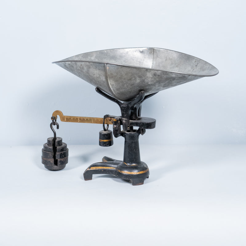 Antique cast iron counter balance scale with original galvanized scoop, brass graduated beam, and cast iron counterweights, vintage early 20th-century general store scale.