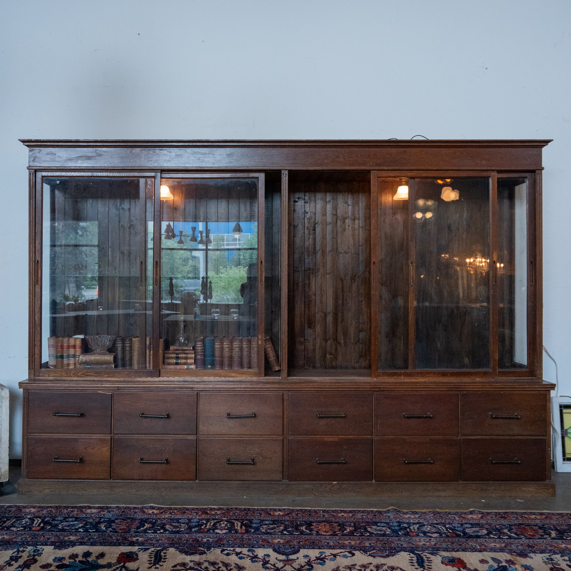 | Antique 10 foot oak general store display cabinet with sliding glass doors and twelve storage drawers from a historic hardware store circa 1910.| Scott Landon Antiques and Interiors.