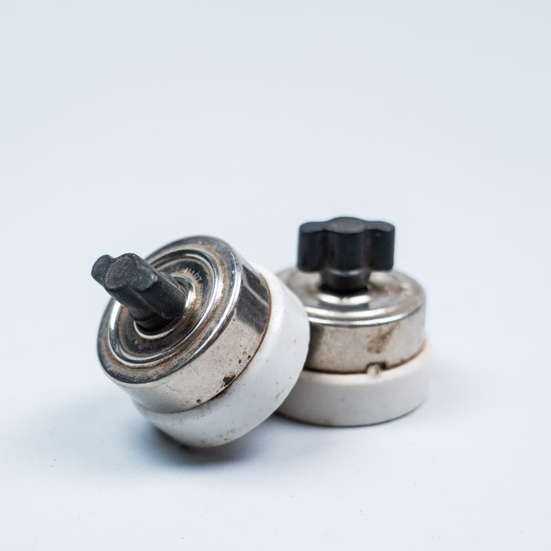 Pair of vintage porcelain push button light switches with black Bakelite buttons and nickel-plated metal housings.