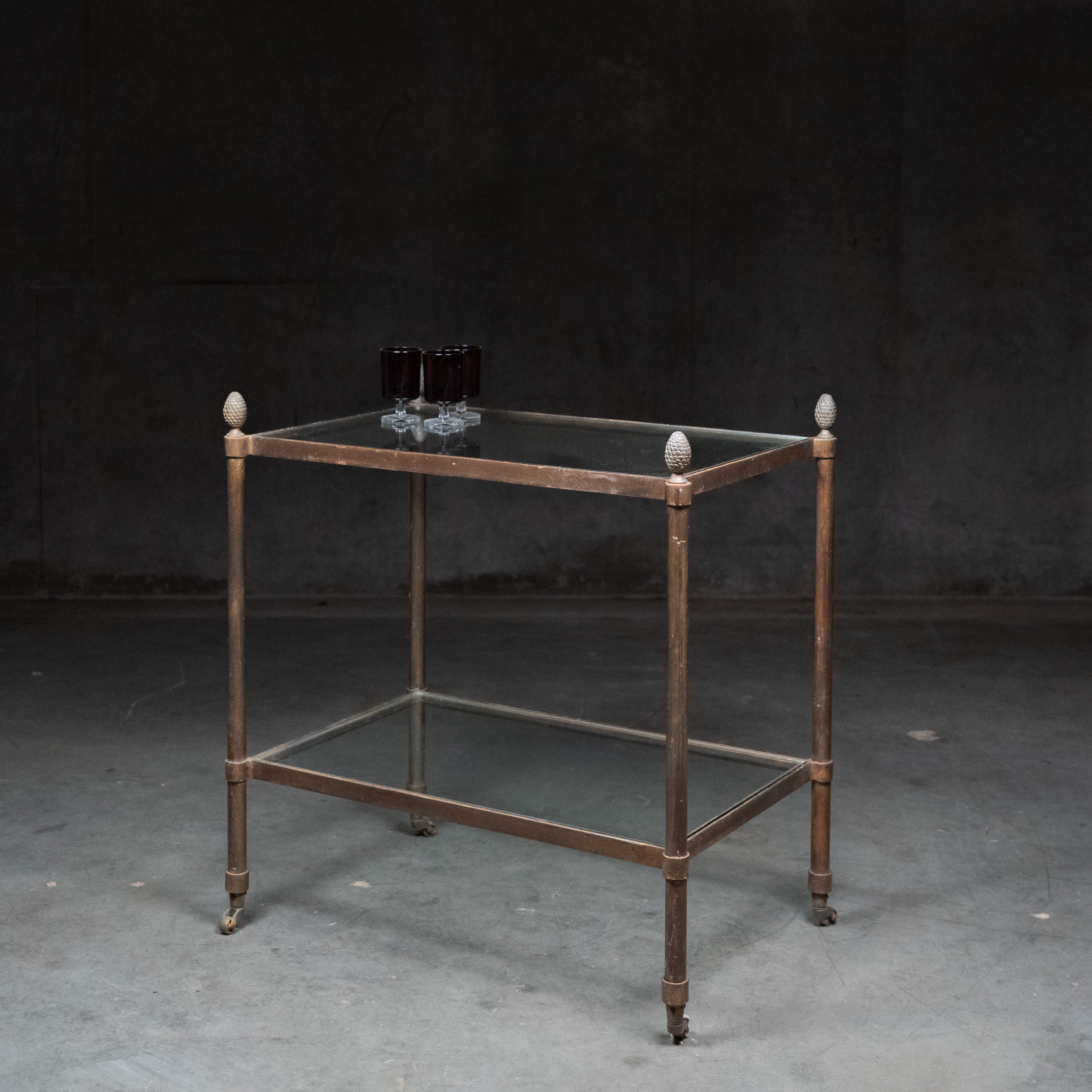 Vintage brass and glass bar cart with pinecone finials and two glass shelves in the Maison Jansen style.