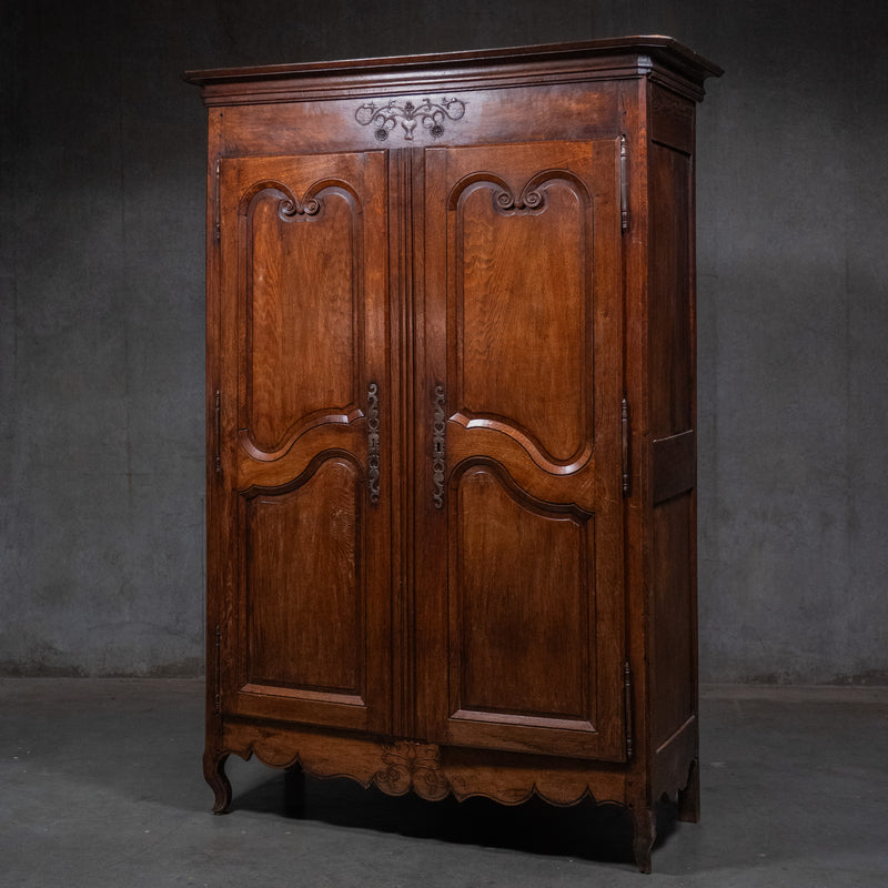 Early 19th-century French provincial solid oak armoire with carved panel doors, pegged construction, and original iron hardware. | Scott Landon Antiques and Interiors.